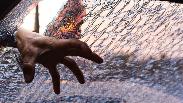 Hand dringt durch das Glas eines Autos ins Fahrzeuginnere